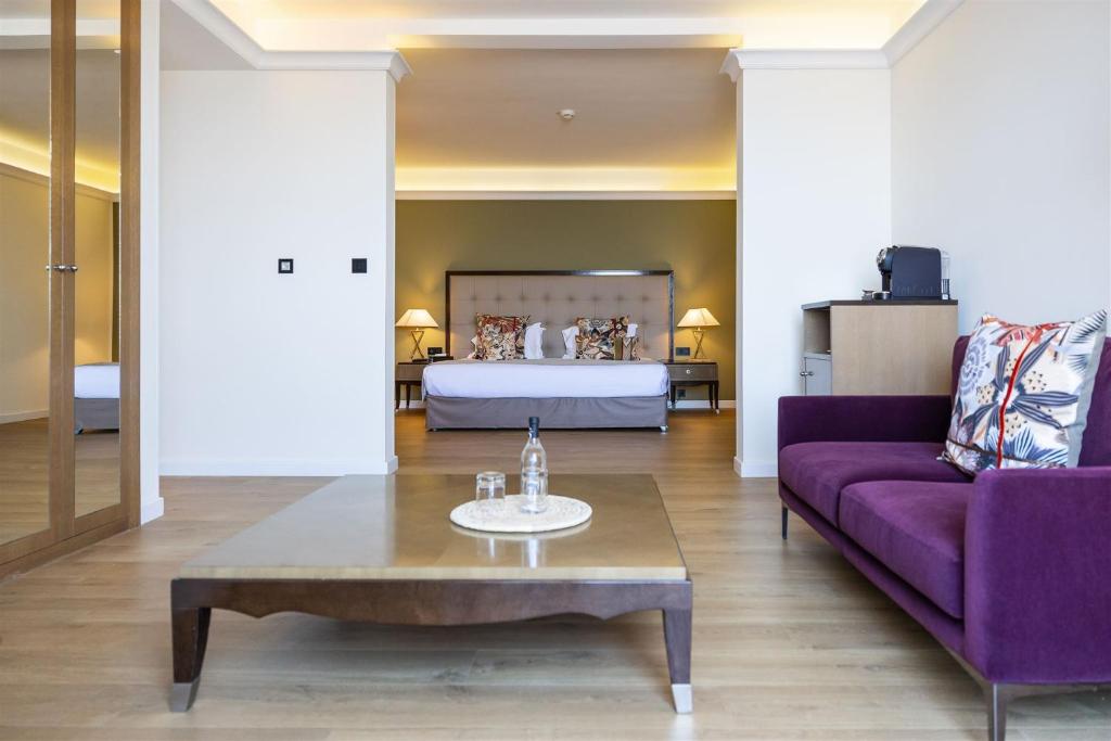 uma sala de estar com um sofá roxo e uma cama em Hôtel Des Gouverneurs em Bastia