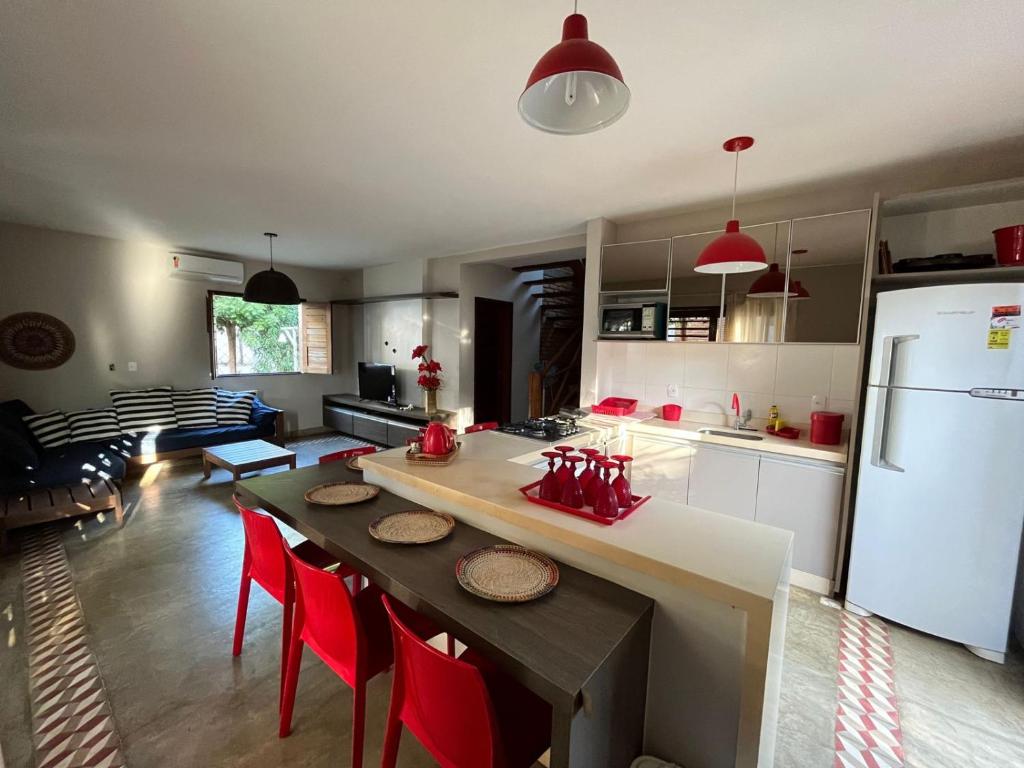a kitchen with a table with red chairs and a refrigerator at Bangalôs da Barra Chalé 3 in Barra Grande