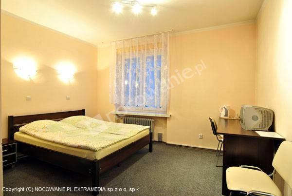 1 dormitorio con cama, escritorio y ventana en Pokoje Gościnne Saritas, en Katowice