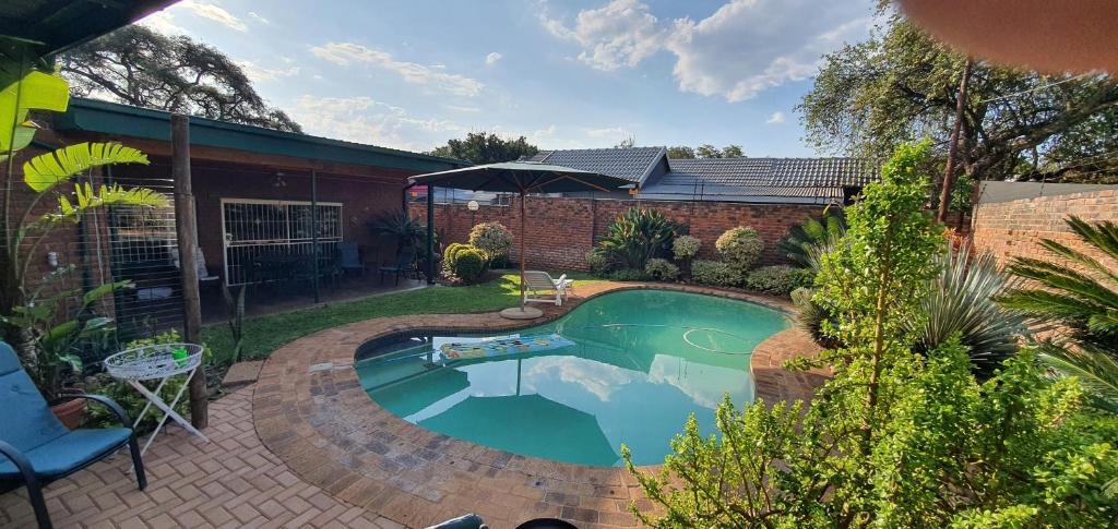 a swimming pool in a yard with a brick house at Emani Guest House in Mokopane