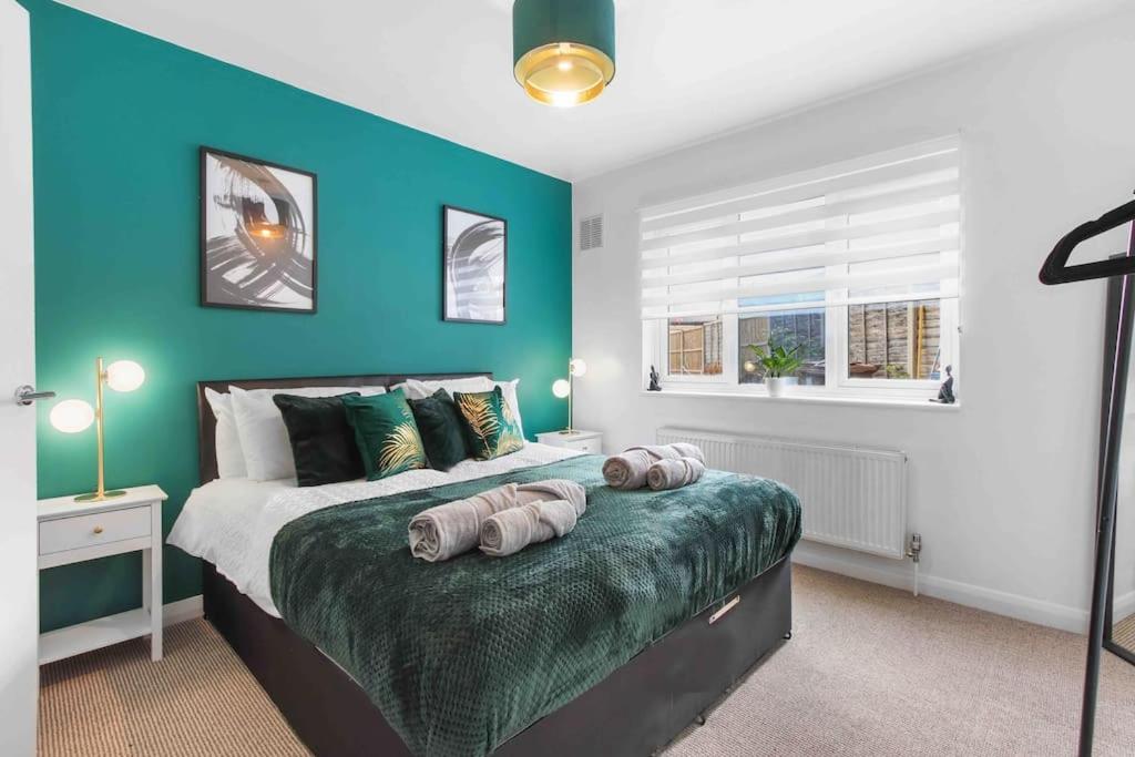 een slaapkamer met een bed met een blauwe muur bij 4 BR House, Kingsize Beds, Free Parking in Farnham Royal