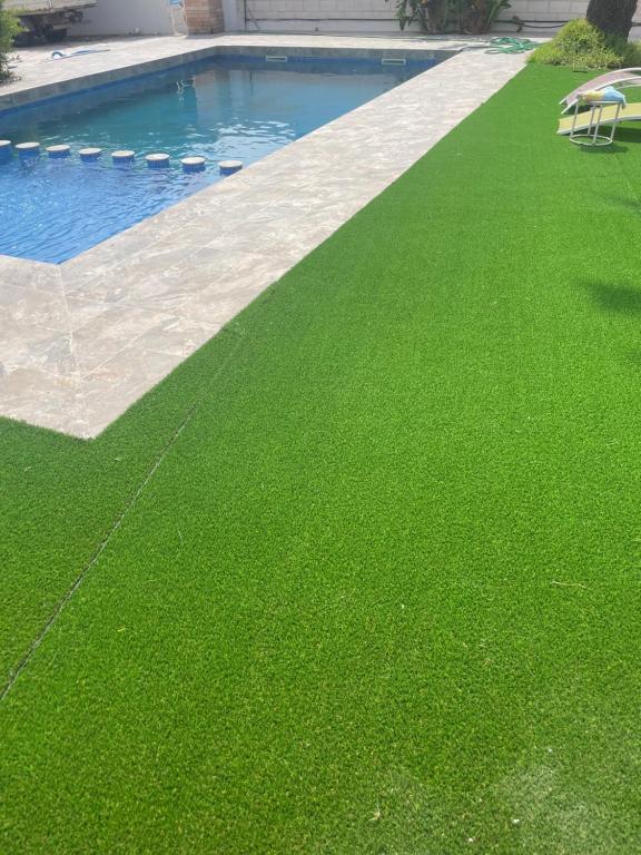 um relvado com relva verde ao lado de uma piscina em Petit paradis 23 em Alicante