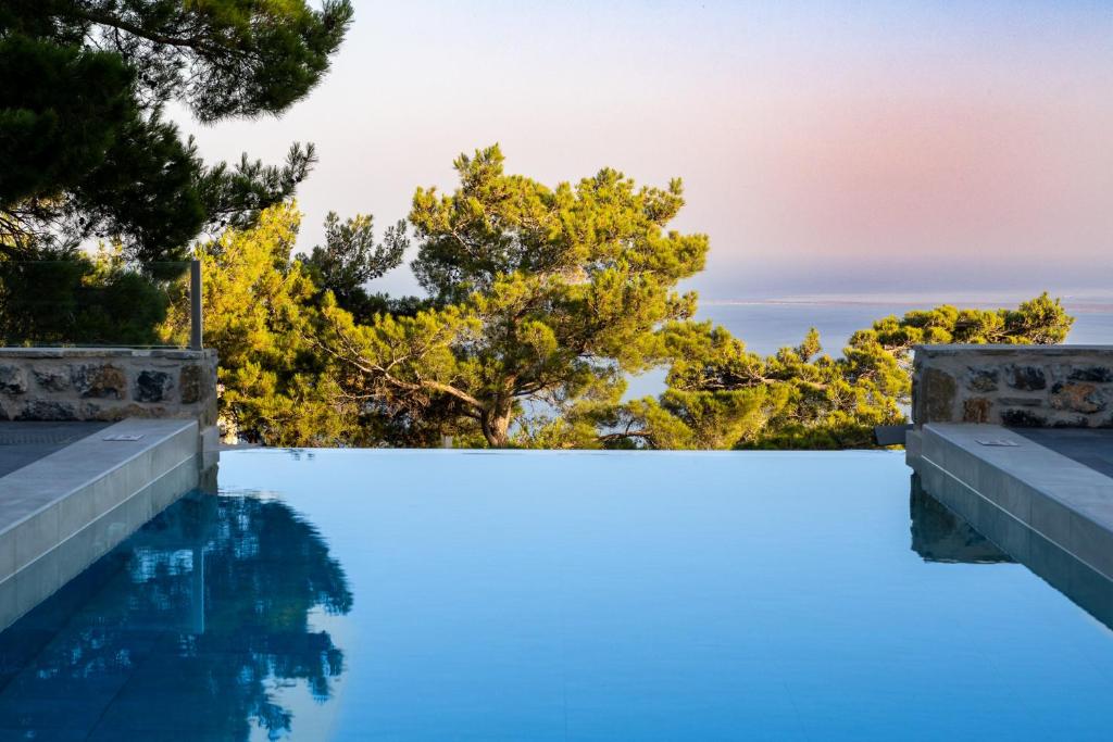 a pool with trees and the ocean in the background at Villa K-Villa with private pool in Ierápetra