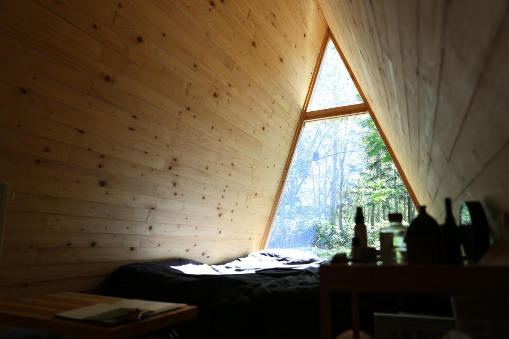 Cette chambre est dotée d'une fenêtre dans un mur en bois. dans l'établissement A-frame cabin iwor - Vacation STAY 36172v, à Shimokawa