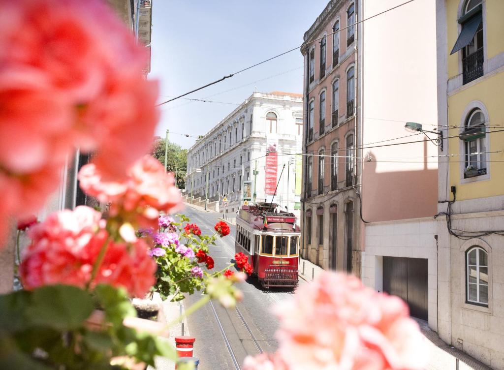 un carro rojo en una calle de la ciudad con flores en Residencial Valentina, en Lisboa