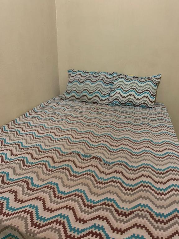 a bed with a striped blanket and a pillow on it at Hospedagem M in Barreirinhas