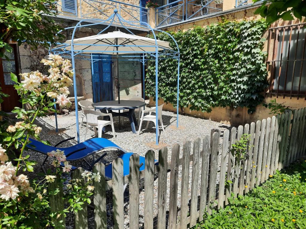 - un jardin avec une table, un parasol et une clôture dans l'établissement Appartement RDC avec terrasse privée, à Castellane