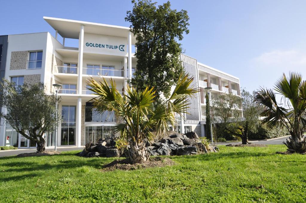 un edificio de oficinas con una palmera delante en Golden Tulip Nantes Carquefou Suite en Carquefou