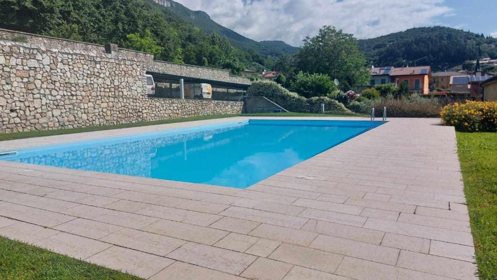 - une piscine dans une cour à côté d'un mur en pierre dans l'établissement Villa Bevilacqua Nuovo bilocale modernopiscina, à Caprino Veronese