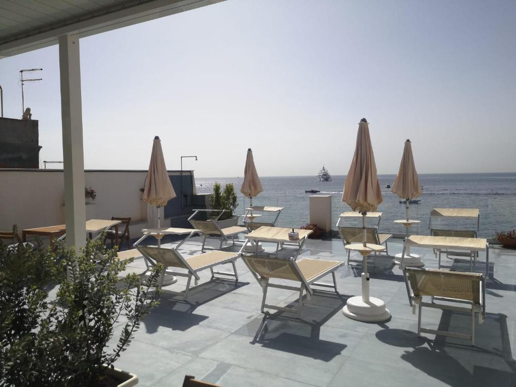 un groupe de chaises, de tables et de parasols dans l'établissement Tulla's, à Giardini Naxos