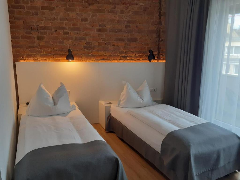 two beds in a room with a brick wall at Hotel Lindenhof in Düsseldorf