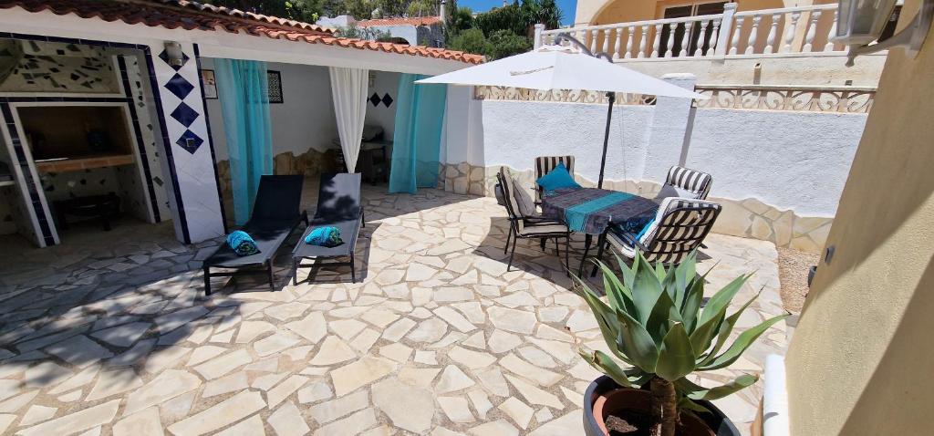 een patio met een tafel en stoelen en een parasol bij Moderne geräumige Ferienwohnung in der Villa Fortuna in Calpe