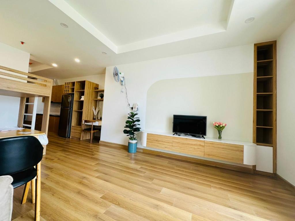 a living room with a television and a wooden floor at TMS Luxury Hotel in Quy Nhon