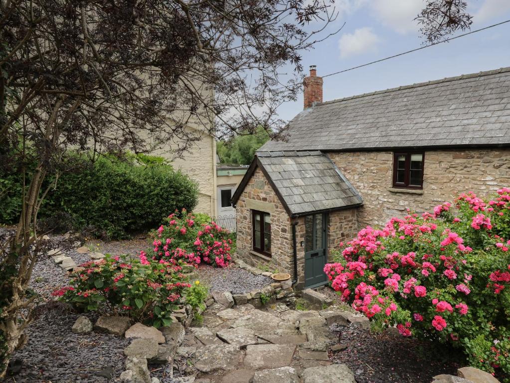 a stone cottage with pink flowers in front of it at Groveside in Hereford