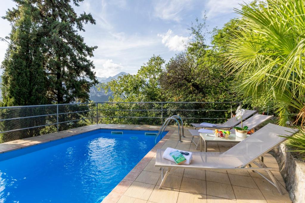 einen Pool mit zwei Stühlen und einem Tisch neben einem Pool in der Unterkunft Villa Panorama with private pool - Happy Rentals in Nago-Torbole