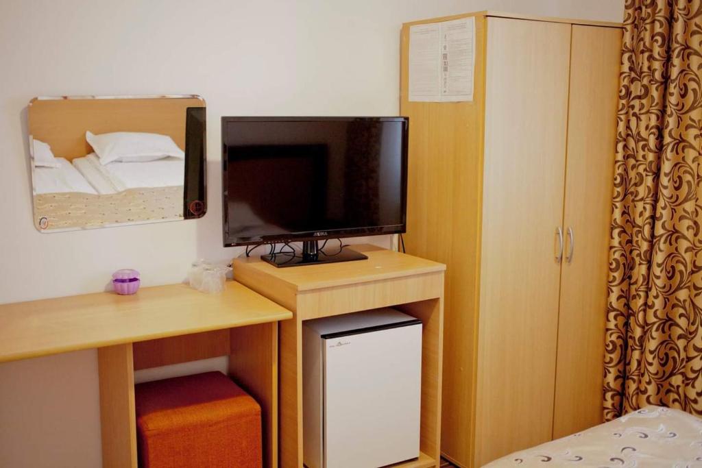 a room with a desk with a television and a bed at Hotel Mya in Bistriţa