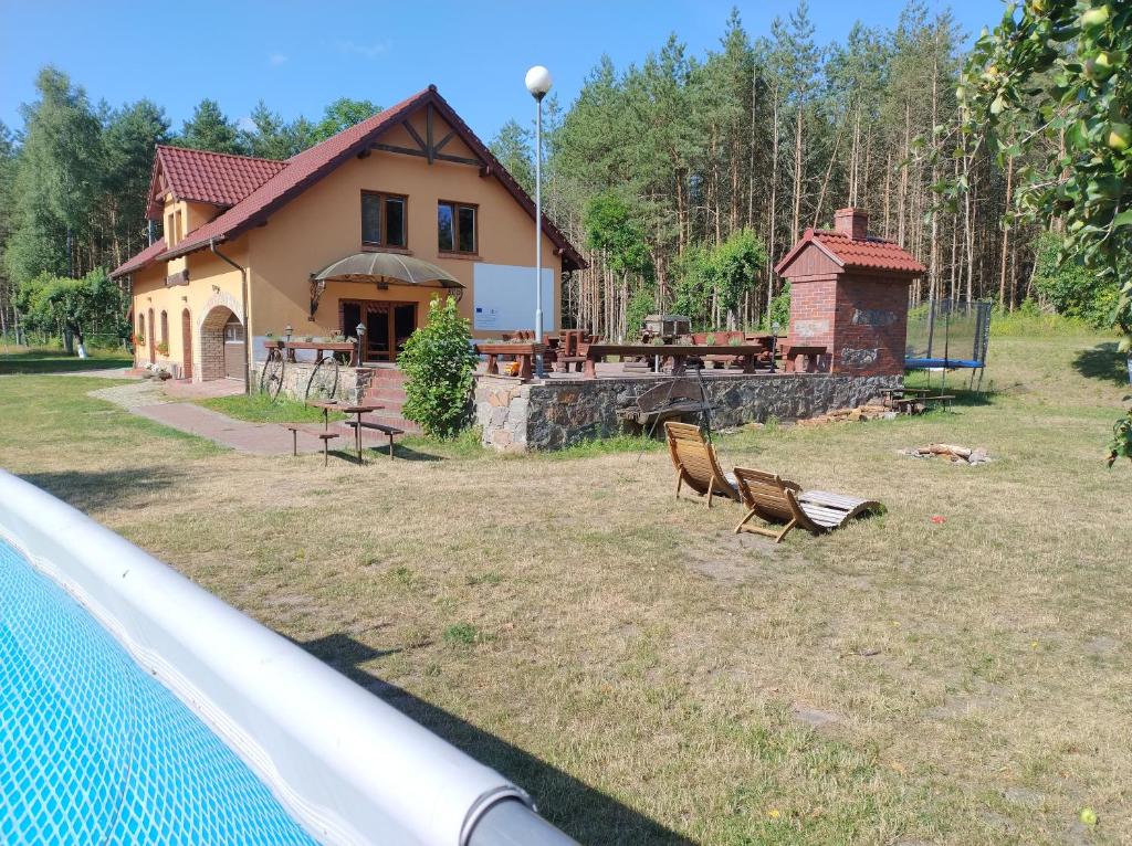 uma casa com um quintal com cadeiras em frente em PENSJONAT W LESIE em Tuczno