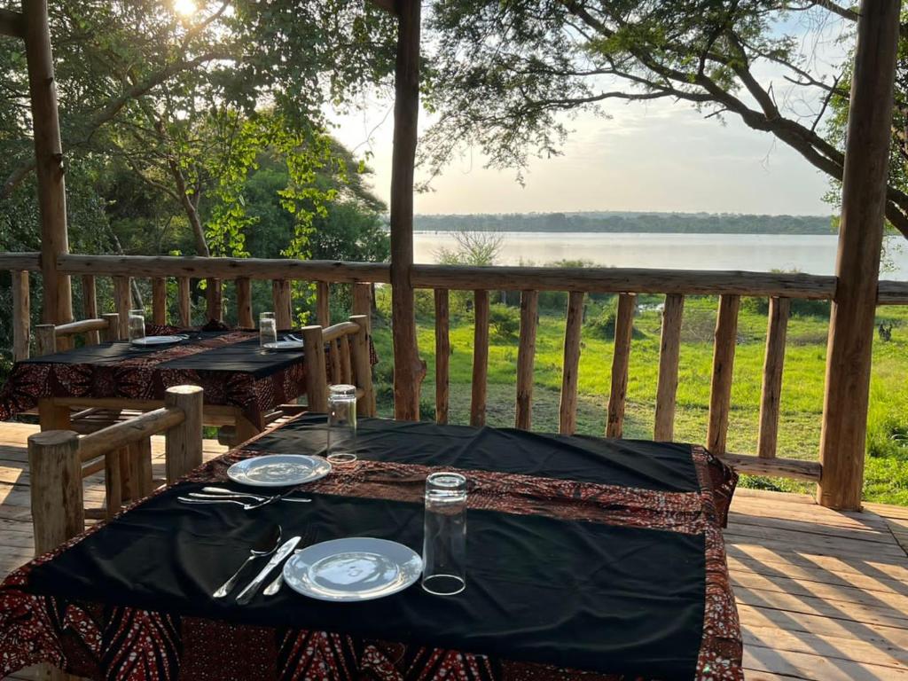 a table set up on a deck with a view of the water at Murchison Giraffe Camp in Murchison Falls National Park