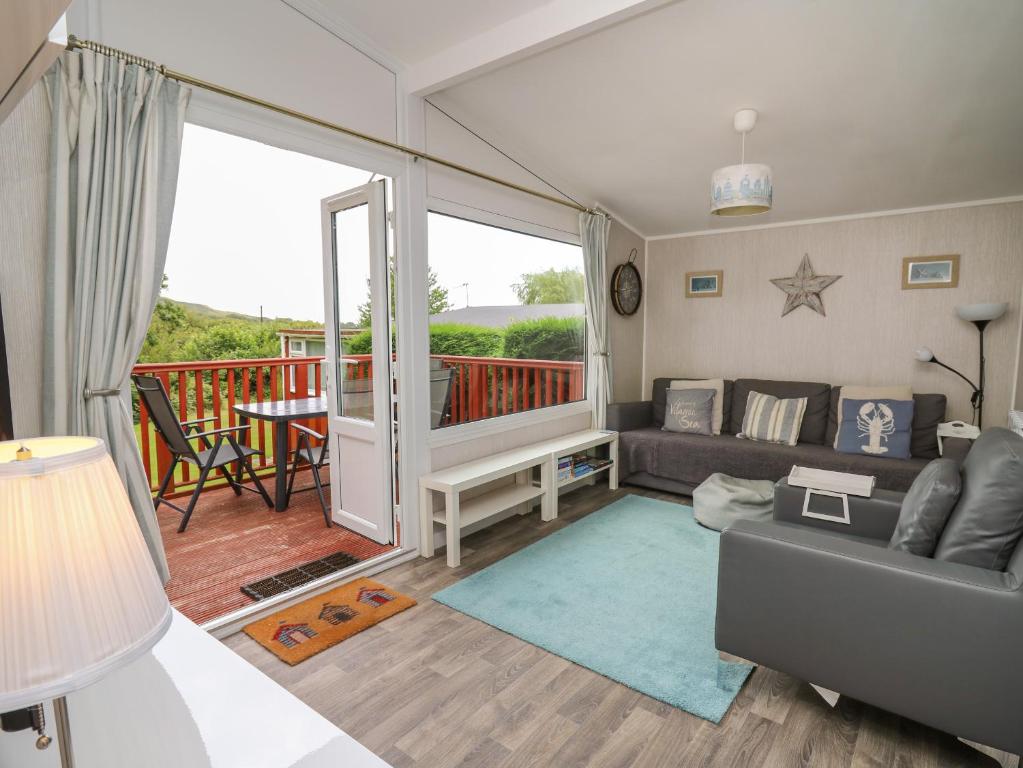 a living room with a couch and a balcony at Chalet 64 in Tywyn