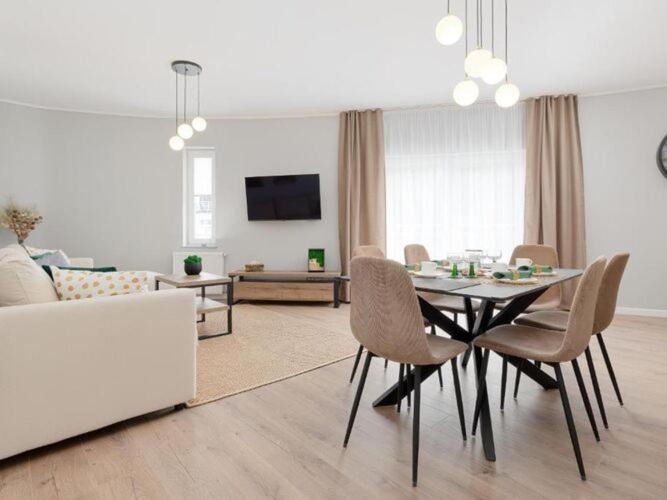 a dining table and chairs in a living room at Spacious apartment, summer swimming pool, Pobierowo in Pobierowo