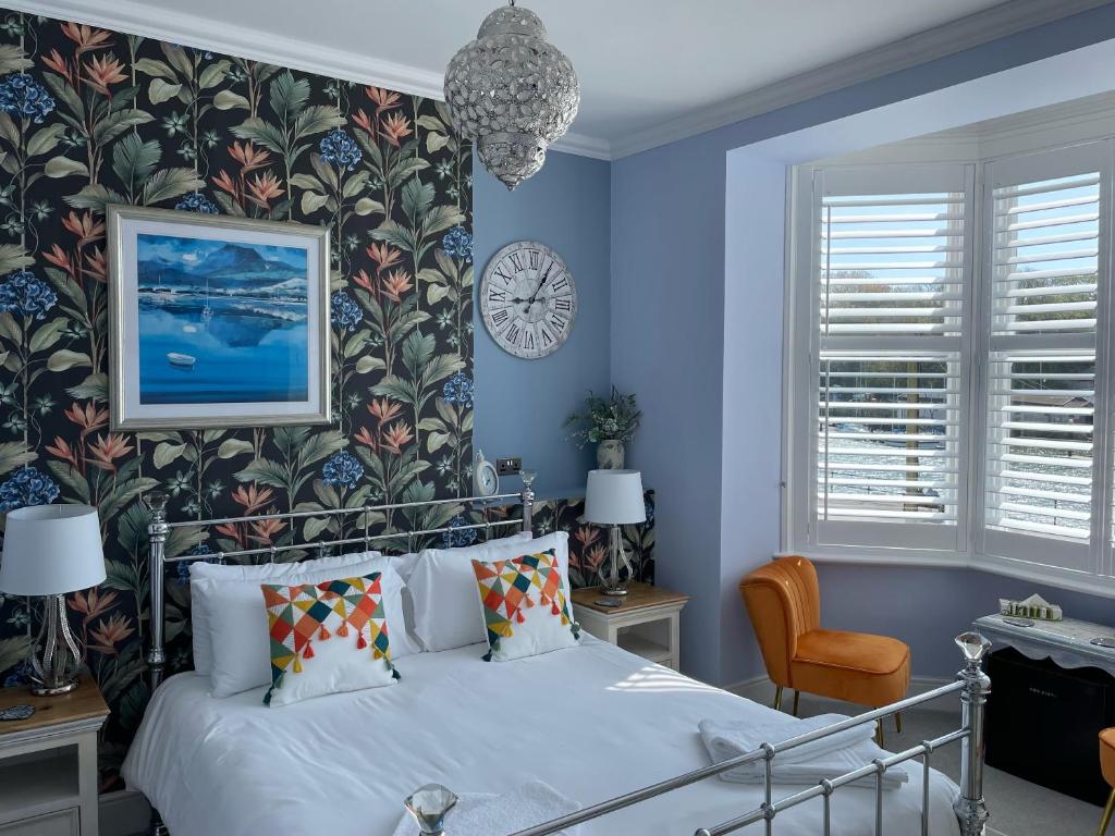 Lantana Guest House في ويماوث: غرفة نوم زرقاء مع سرير وساعة على الحائط