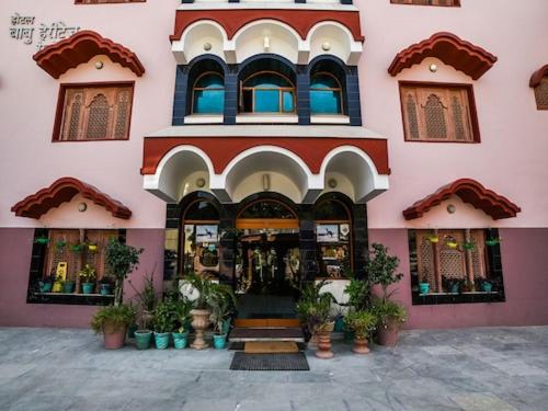 um edifício cor-de-rosa com plantas à sua frente em hotel babu heritage em Bikaner