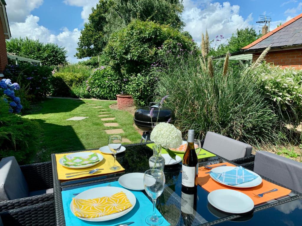 a table with plates of food and a bottle of wine at Delightful 1 bed, 1 bath Norfolk Broads Guesthouse in Halvergate