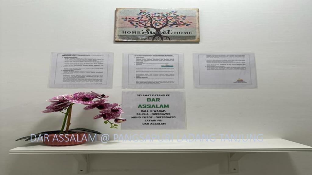 uma flor num vaso numa prateleira com certificados em Ladang Tanjung Dar Assalam Homestay em Kuala Terengganu