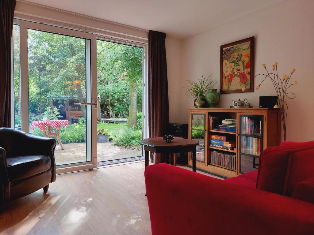 ein Wohnzimmer mit einer roten Couch und einer Glasschiebetür in der Unterkunft KnusinTwente in Geesteren