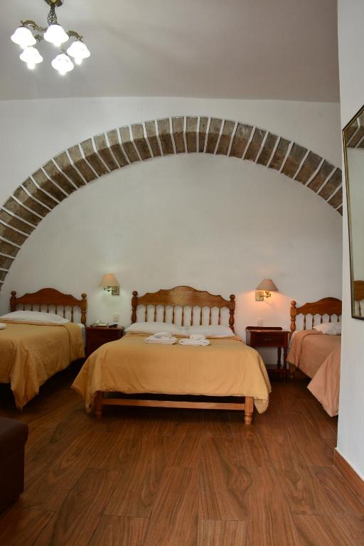 a bedroom with two beds in a room with an arch at Hotel Santa Rosa in Ayacucho
