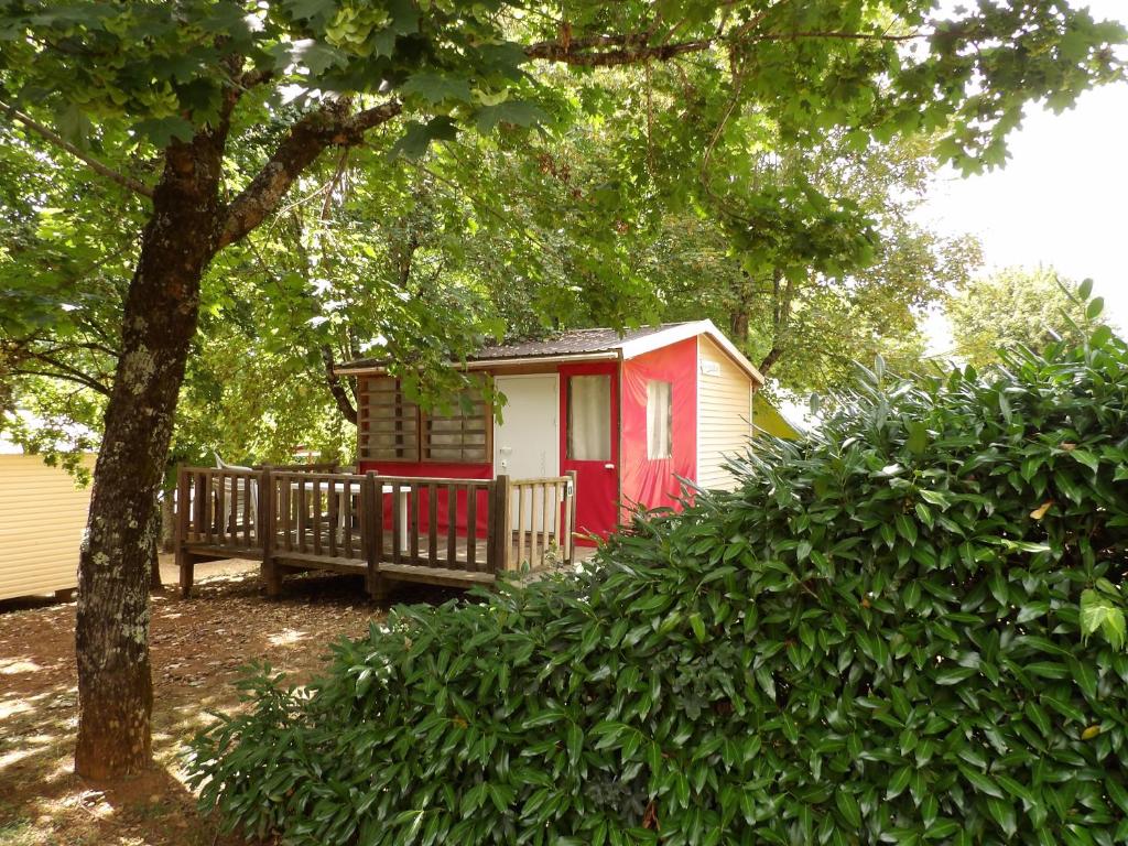uma pequena cabana vermelha e branca na floresta em THITOME em Limeuil