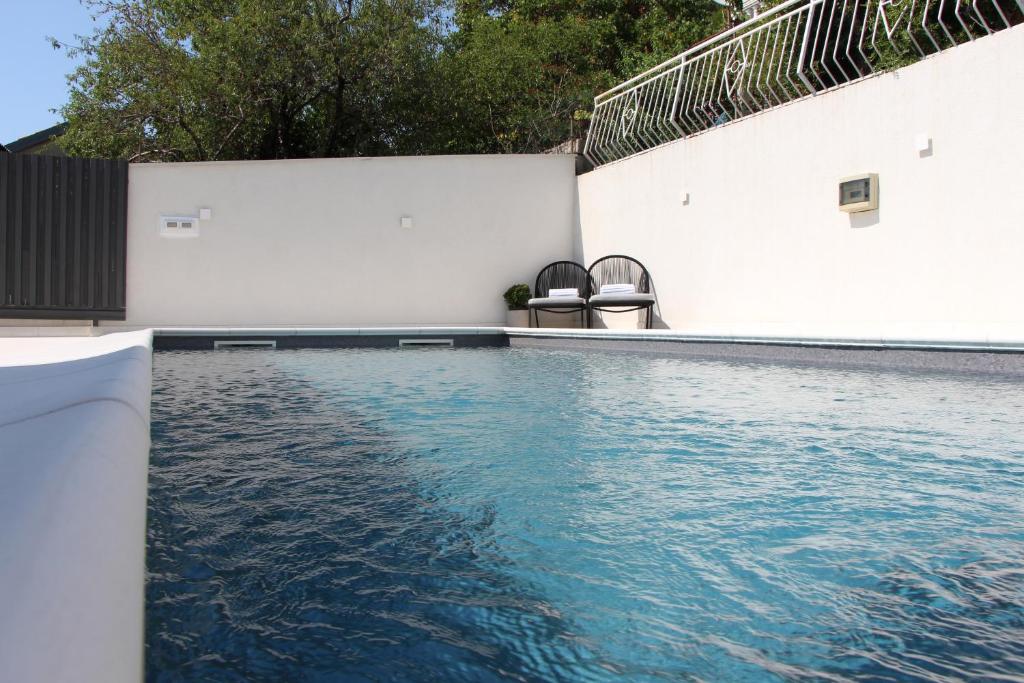 a swimming pool with blue water next to a white wall at MARIAS in Senj