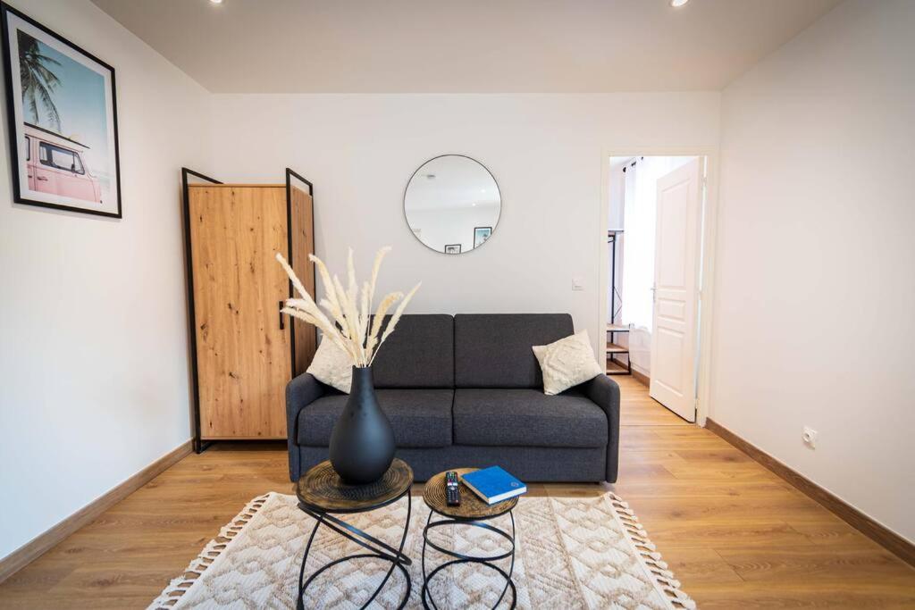 una sala de estar con un sofá negro y un jarrón sobre una mesa en L'Albatros 009 - Hypercentre * Cosy * Wifi, en Saint-Quentin