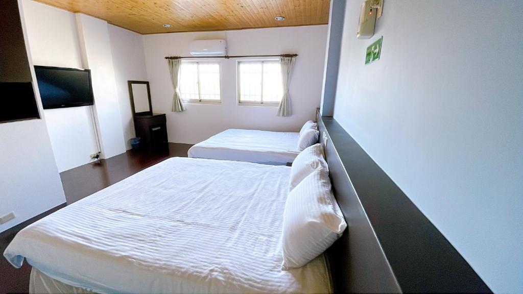 a room with two beds and a tv at Sun B&amp;B in Taitung City