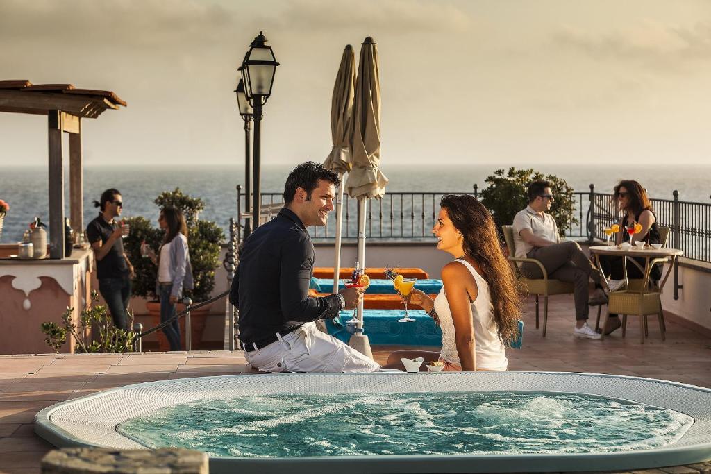 a man and a woman standing next to a hot tub at Hotel Nettuno in Ischia