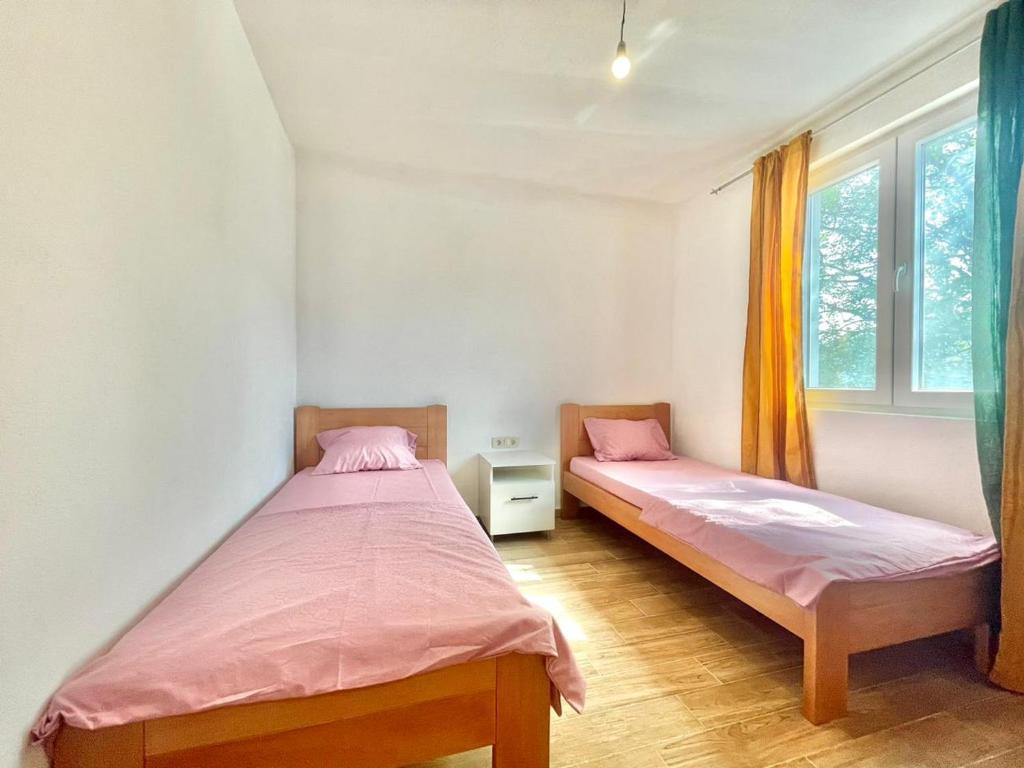 2 Einzelbetten in einem Zimmer mit 2 Fenstern in der Unterkunft Talia Apartments in Budva