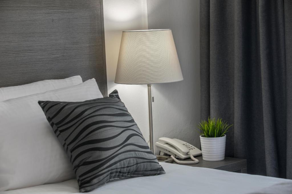 a bedroom with a bed with a lamp and a phone at Blazer Residence in Larnaka