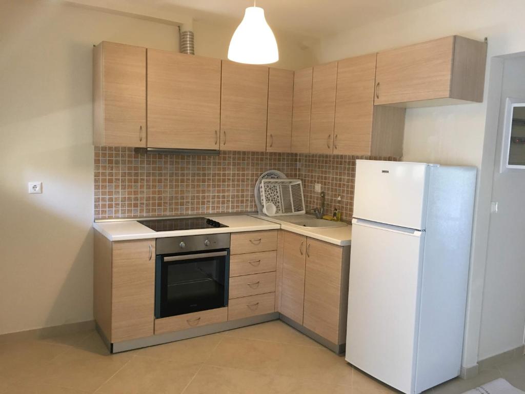 eine Küche mit Holzschränken und einem weißen Kühlschrank in der Unterkunft Spacious Apartment Skala Fourkas in Skála Foúrkas