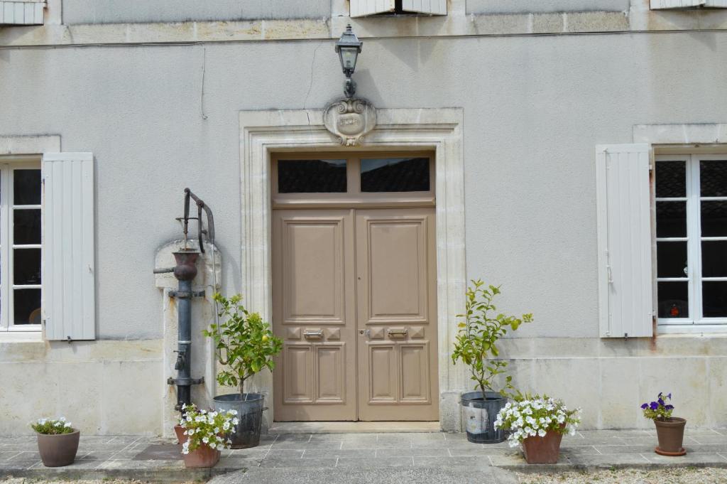 a door with two potted plants in front of a building at La Vieille Distillerie in Le Tâtre