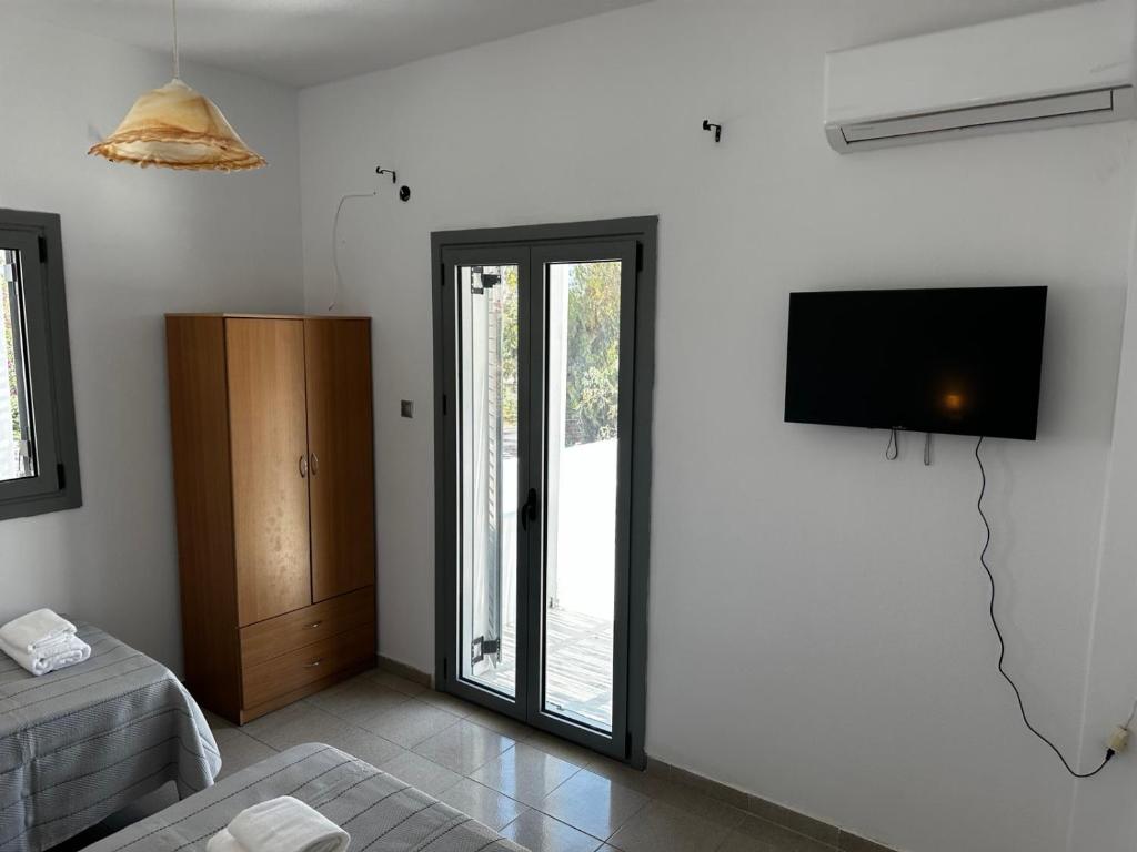 uma sala de estar com uma televisão de ecrã plano na parede em Santorini Style Rooms em Vóthon
