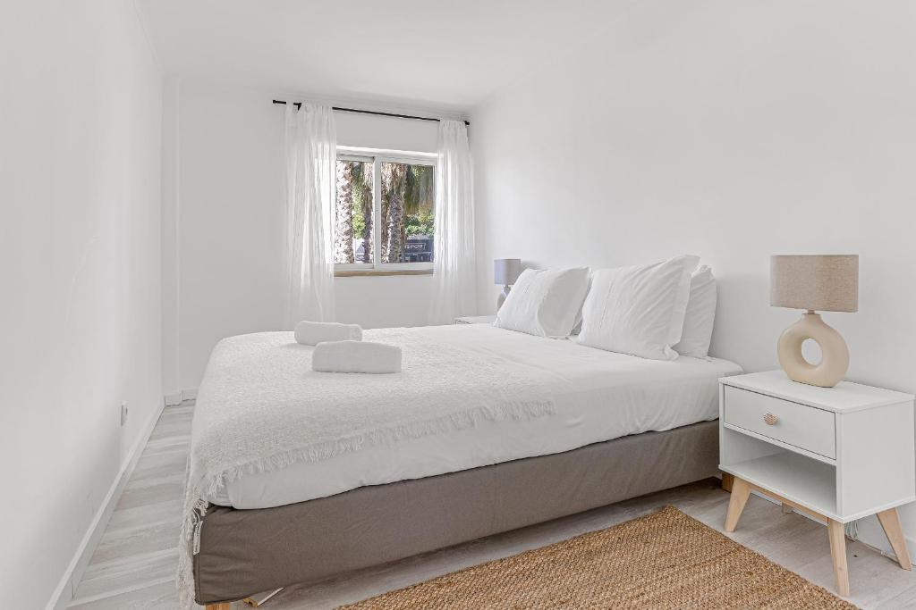 a white bedroom with a bed and a window at Bright Alges Apartment in Algés