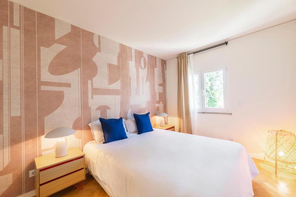- une chambre avec un grand lit blanc et des oreillers bleus dans l'établissement Olala Ribeira Apartment, à Cascais
