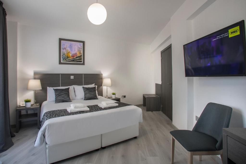 a bedroom with a bed and a tv and a chair at Blazer Residence in Larnaka