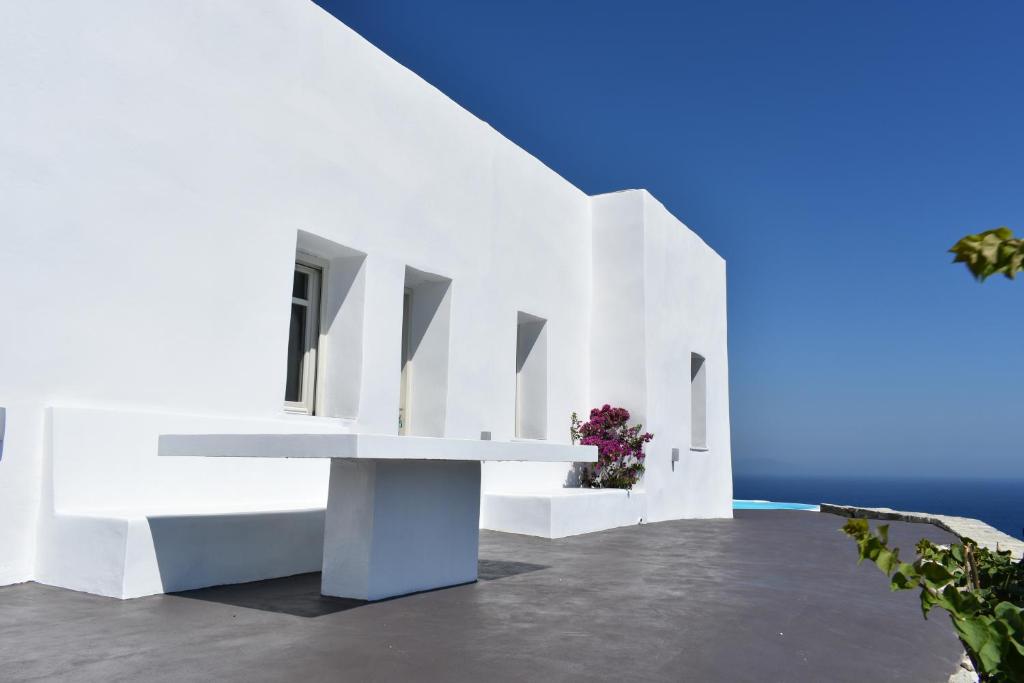 una casa blanca con un banco y el océano en CALDERA CASABLANCA, en Áno Meriá