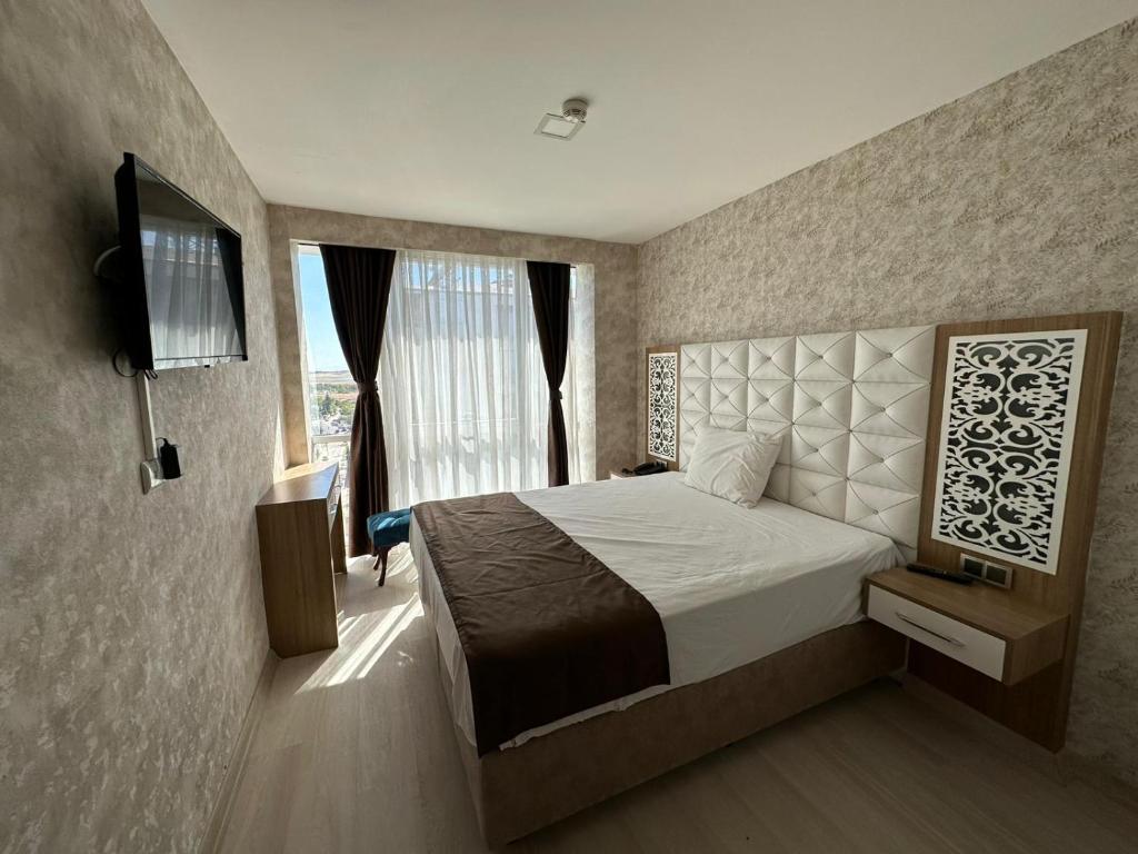 una camera con letto, TV e finestra di GrandPazarcıkOtel 