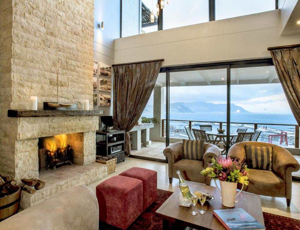 a living room with a fireplace and a view of the ocean at Mariner Guesthouse & Villa in Simonʼs Town