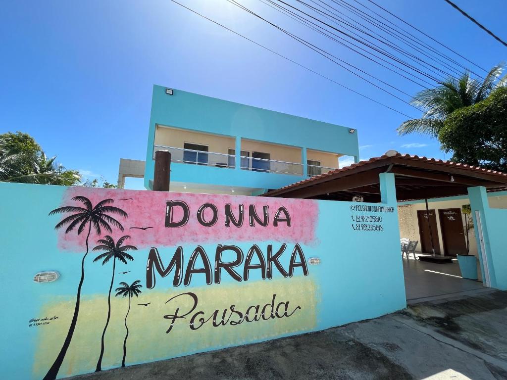un panneau devant une maison avec un palmier dans l'établissement Pousada Donna Maraka, à Porto de Galinhas