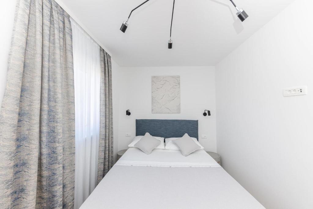 Apartments Antico في تروغير: غرفة نوم بيضاء مع سرير وستائر