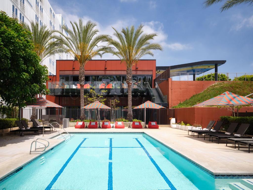 a swimming pool in front of a building with palm trees at Aloft El Segundo - Los Angeles Airport in El Segundo