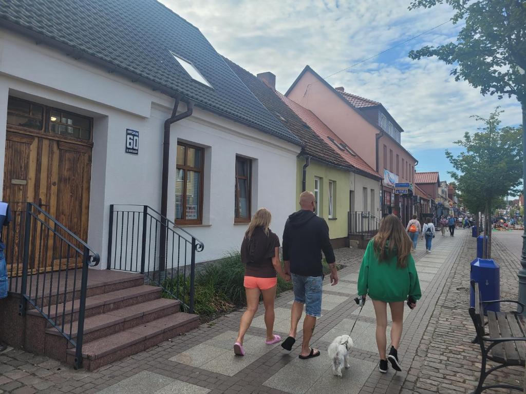 a group of people walking a dog down a street at Apartamenty Majer Łeba Centrum in Łeba